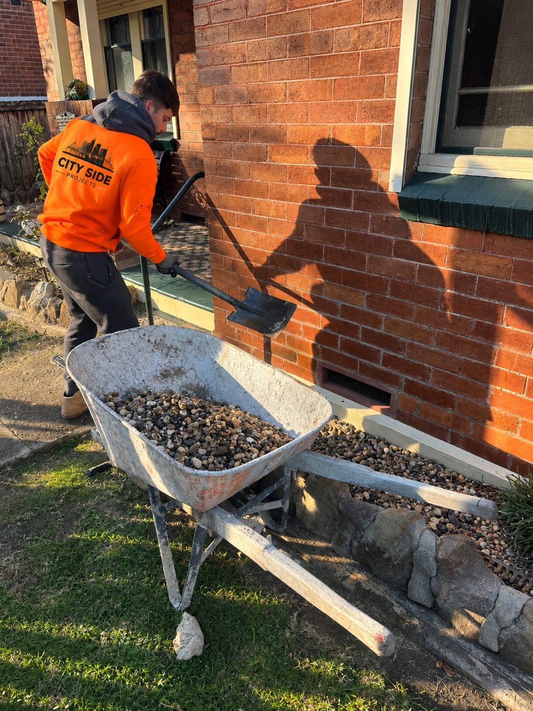 City Side worker excavating beside brick dwelling